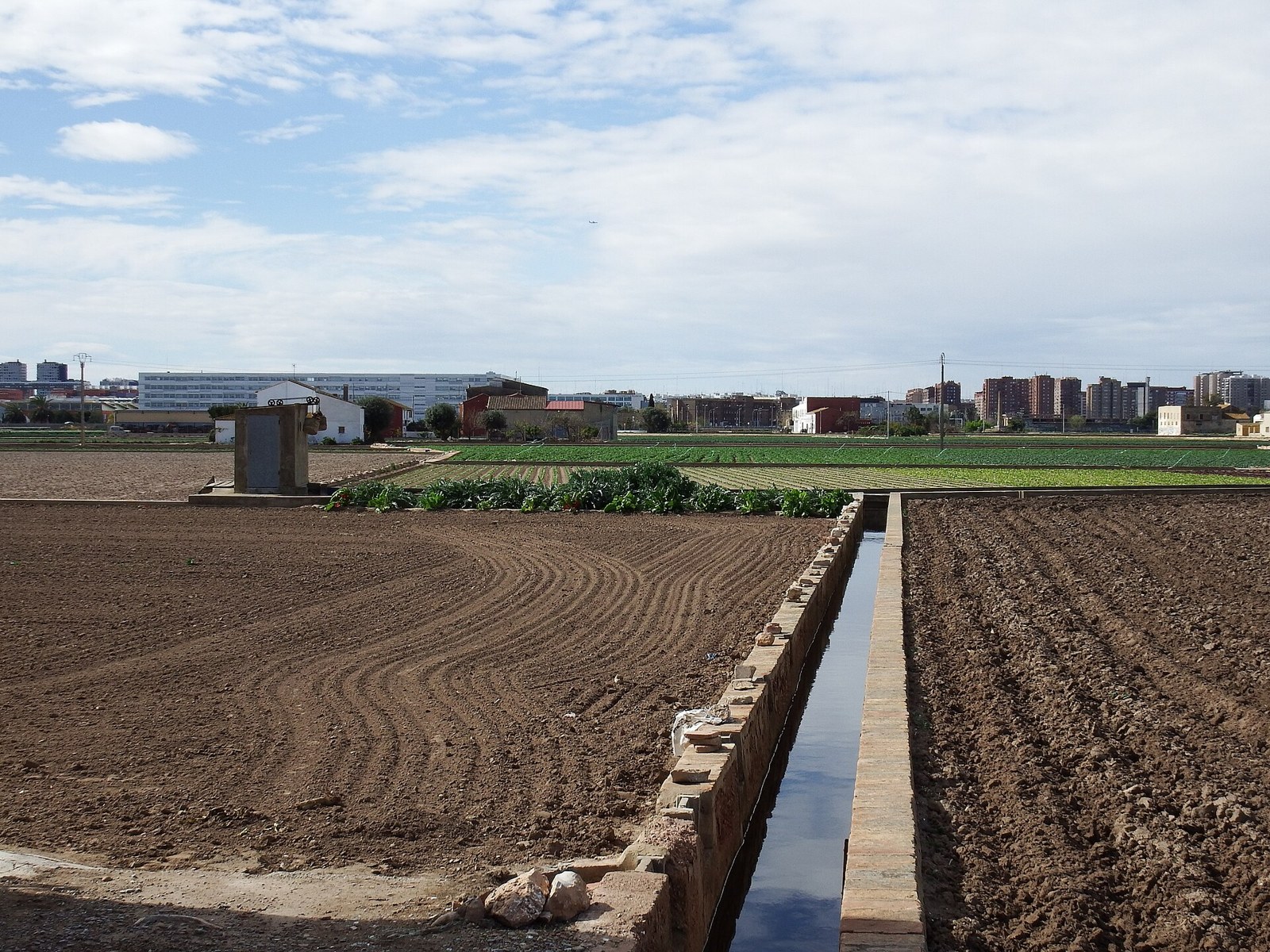 Acequia de ladrillo entre parcelas recién labradas en la huerta de Alboraia